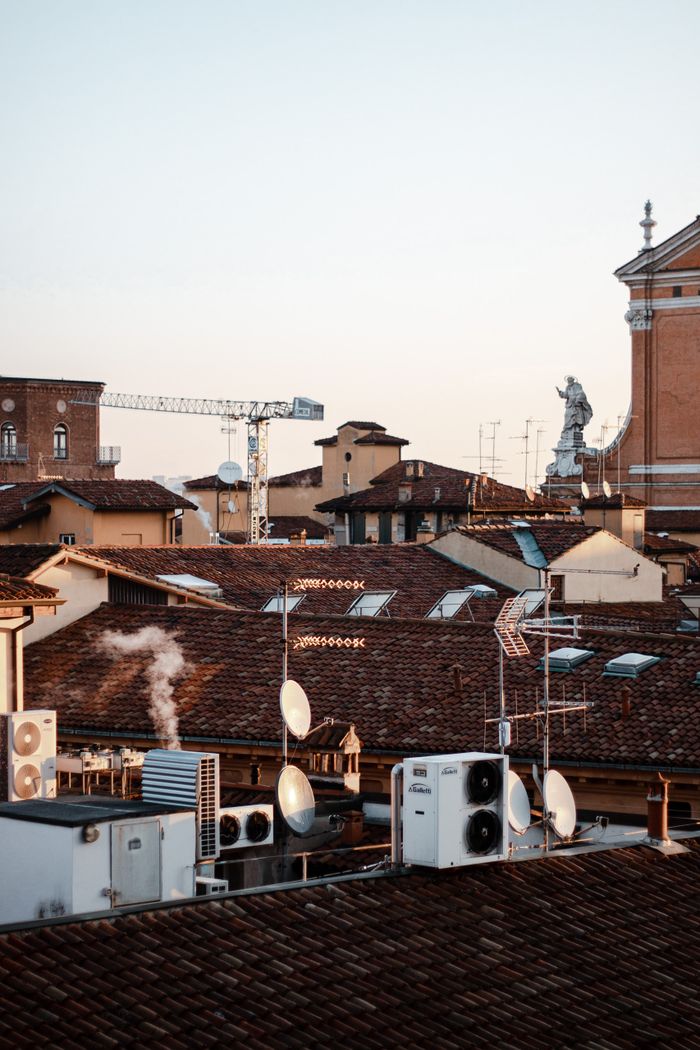 Services A scenic view of Bologna rooftops with antennas and equipment at dusk, capturing urban charm.