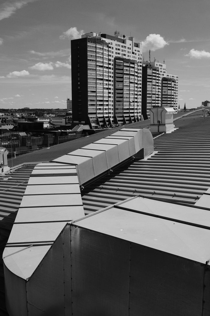 Services Black and white photograph of modernist buildings with rooftop air ducts, under a clear sky.